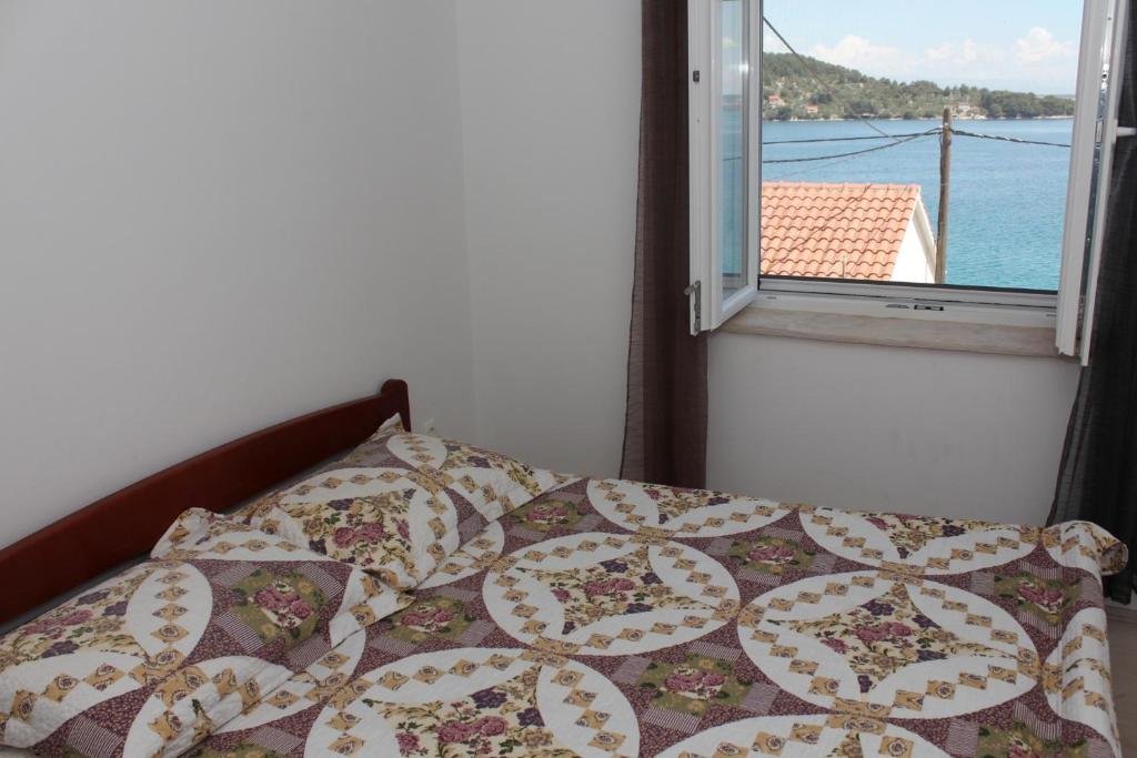 ein Bett mit einer Decke und einem Fenster in einem Schlafzimmer in der Unterkunft Apartments by the sea Kali, Ugljan - 13865 in Kali