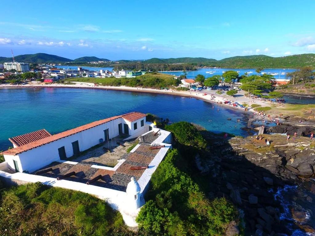 vista aerea di una spiaggia con un edificio di ** SUITE PRIVATIVA PRAIA DO FORTE CABO FRIO ** a Cabo Frio