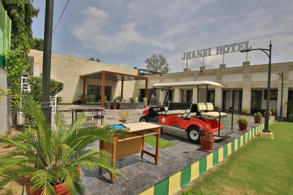 a small red car parked in front of a building at Jhansi Hotel in Jhānsi