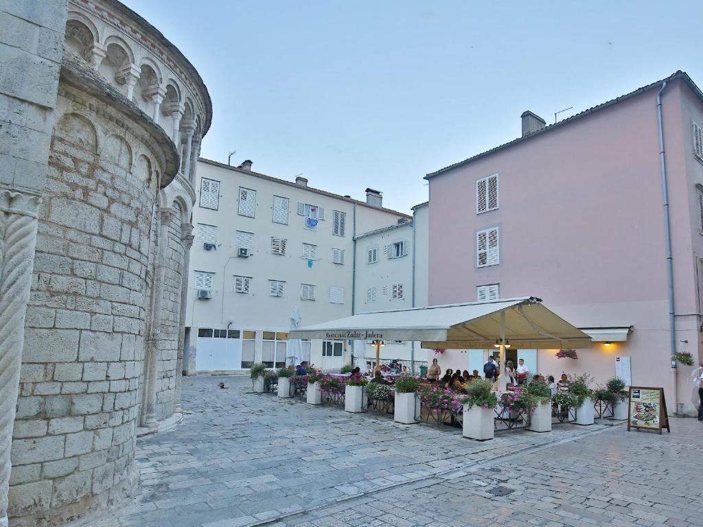 a courtyard with a group of plants and an umbrella at Rooms by the sea Zadar - 14007 in Zadar