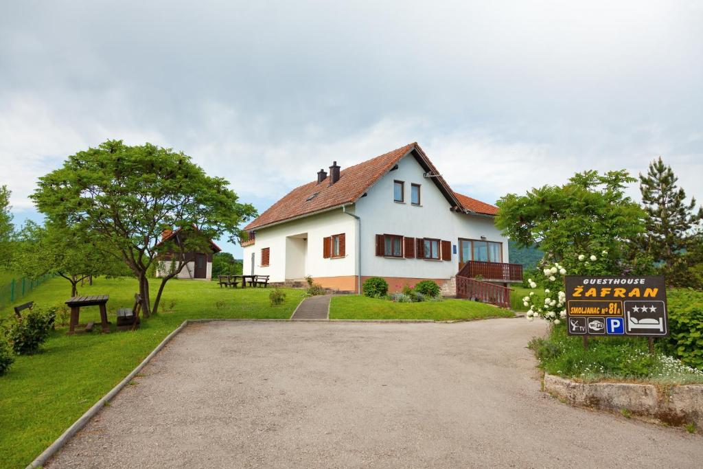 a white house with a sign in front of it at Apartments and rooms with parking space Smoljanac, Plitvice - 14023 in Smoljanac
