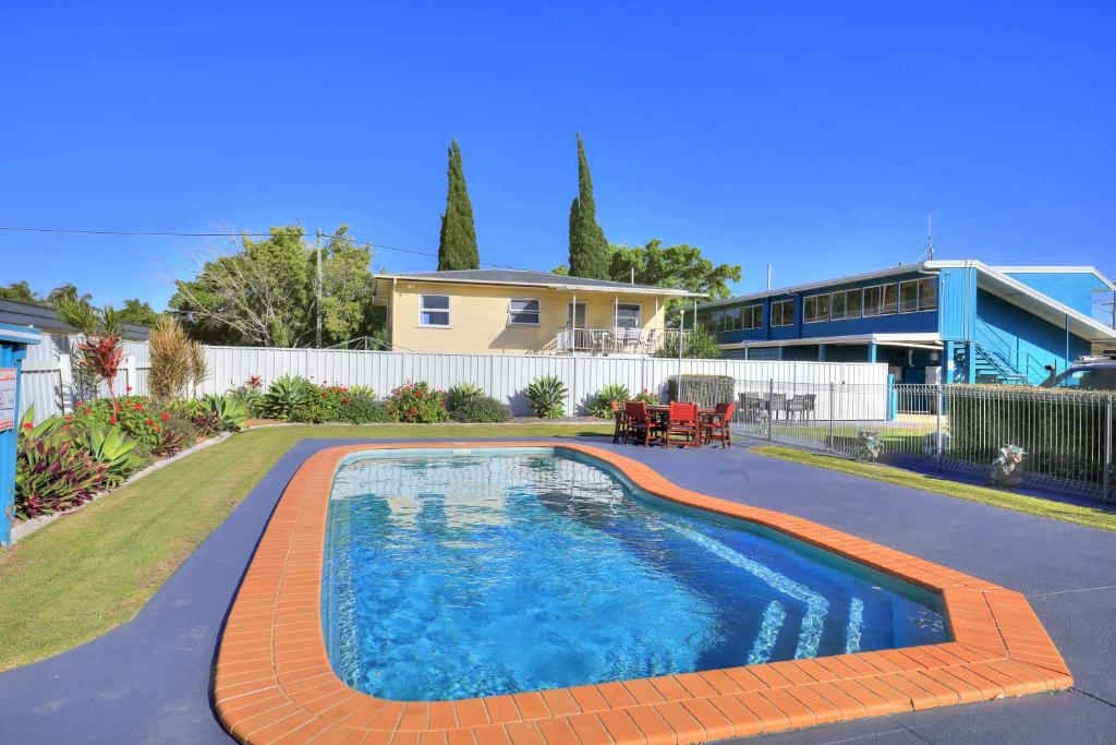 a swimming pool in a yard next to a house at Oscar Motel in Bundaberg