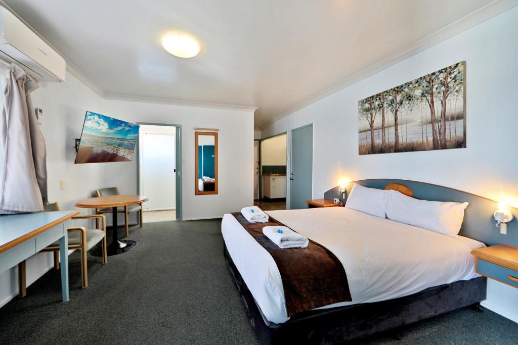 Habitación de hotel con cama grande y escritorio. en Oscar Motel en Bundaberg