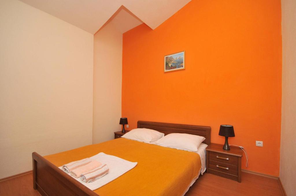 sypialnia z pomarańczową ścianą i łóżkiem w obiekcie Apartments with a parking space Okrug Donji, Ciovo - 13732 w mieście Okrug Donji