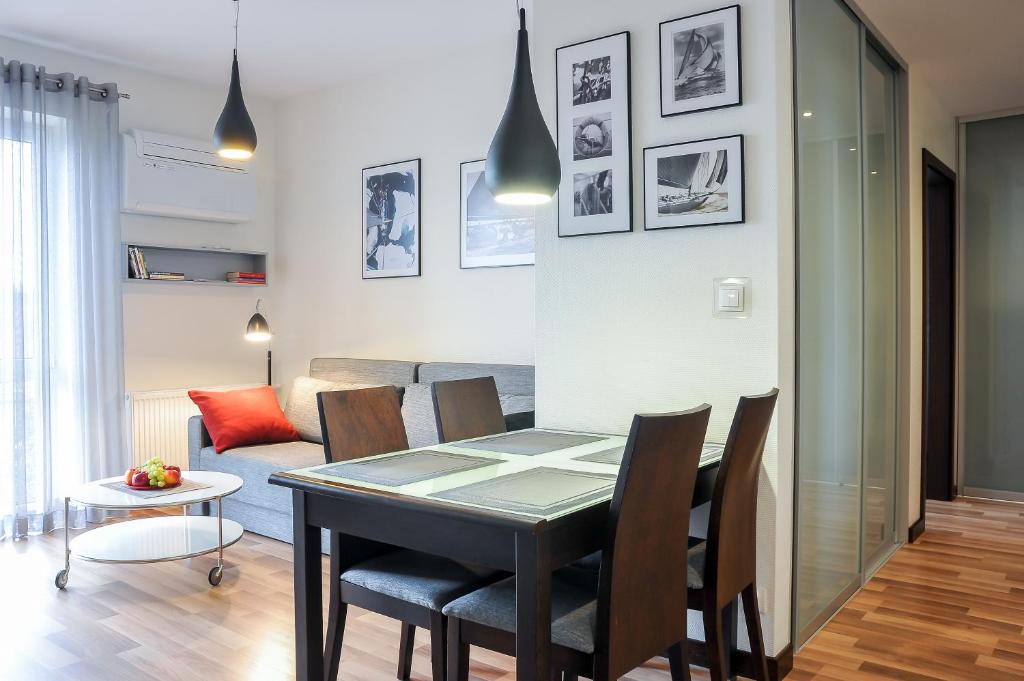 a dining room and living room with a table and chairs at Apartamenty Starówka - Riverside in Szczecin