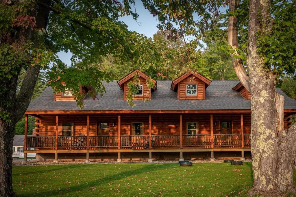 a large log cabin with a wrap around porch at New England Inn & Lodge in North Conway