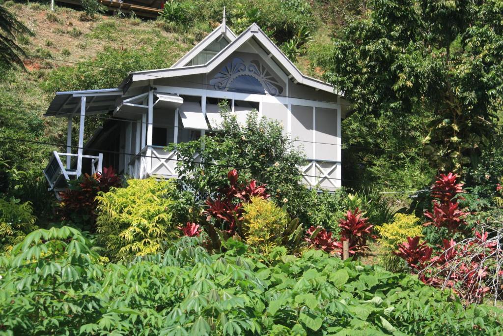 a white house in the middle of a garden at Gingerbread Cottage and Studio Fiji in Savusavu