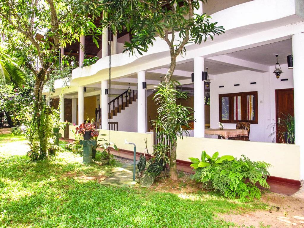 una casa con árboles y césped delante de ella en C-Lanka Guest House en Aluthgama