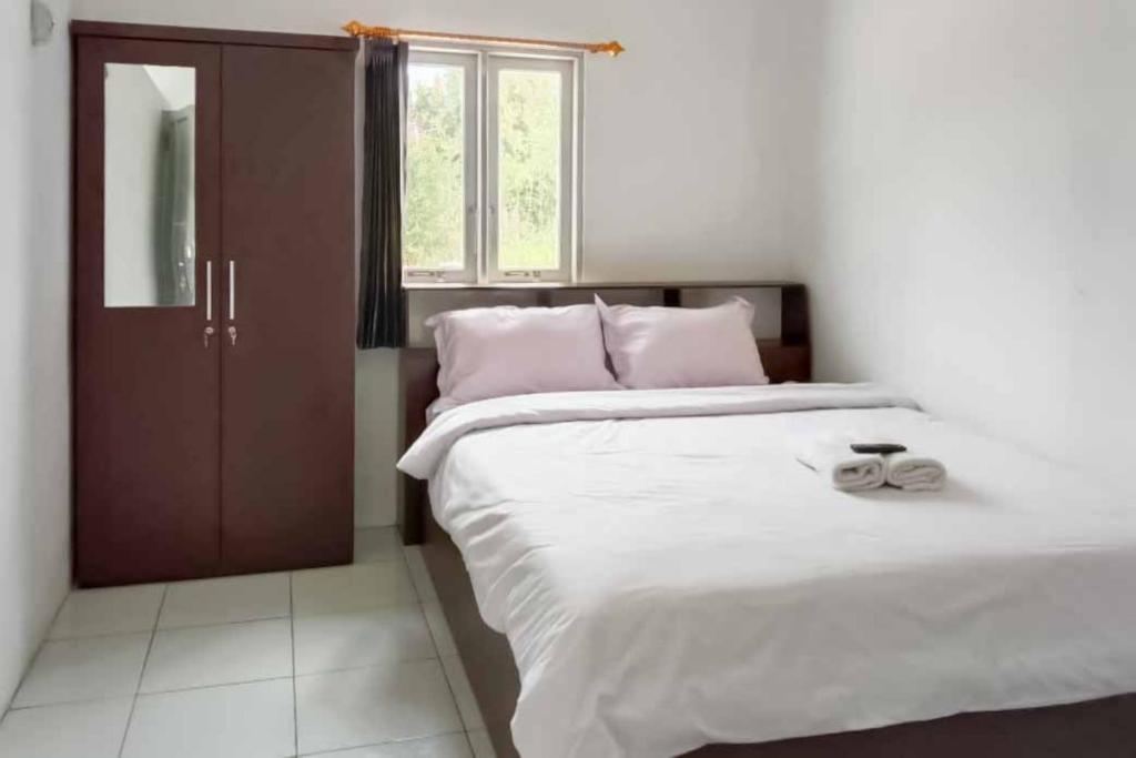 RedDoorz near Universitas Palangkaraya 2 في بالانجكارايا: غرفة نوم بسرير كبير مع شراشف بيضاء ومخدات وردية