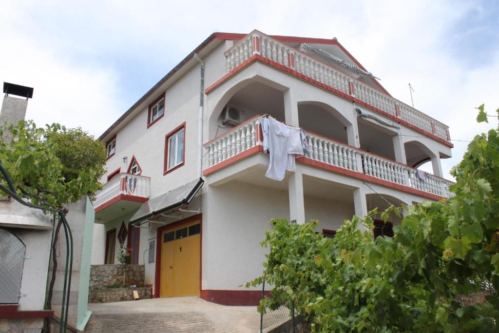 a white building with a orange door and balcony at Apartments by the sea Kali, Ugljan - 8234 in Kali