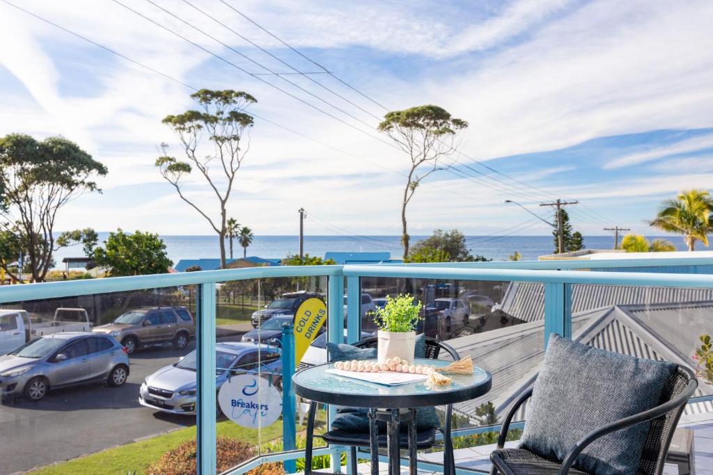 a balcony with a table and chairs and a parking lot at Breakers 5 in Mollymook