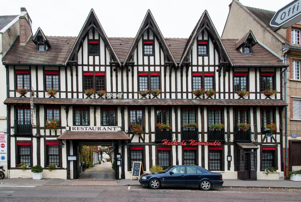 a building with a car parked in front of it at Hotel de Normandie in Évreux