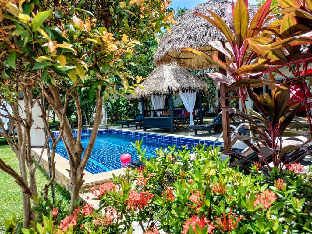 una piscina in un giardino con alberi e fiori di Wirason Residence a Lamai Beach