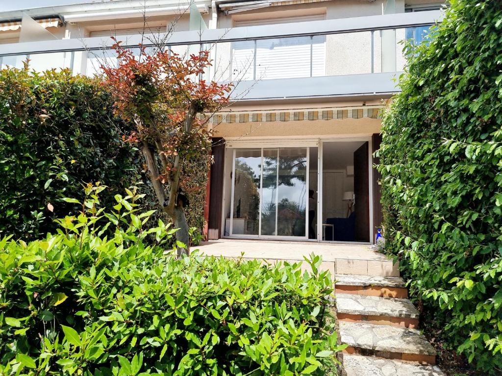 une maison avec une porte en verre et quelques buissons dans l'établissement Charmant T2 avec Terrasse et Jardin Clos à 200m de la Plage - Parking Privé Inclus - FR-1-71-94, à Royan