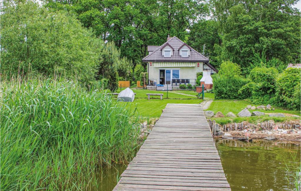 a wooden bridge leading to a house and a pond at Gorgeous Home In Nowe Warpno With House Sea View in Nowe Warpno