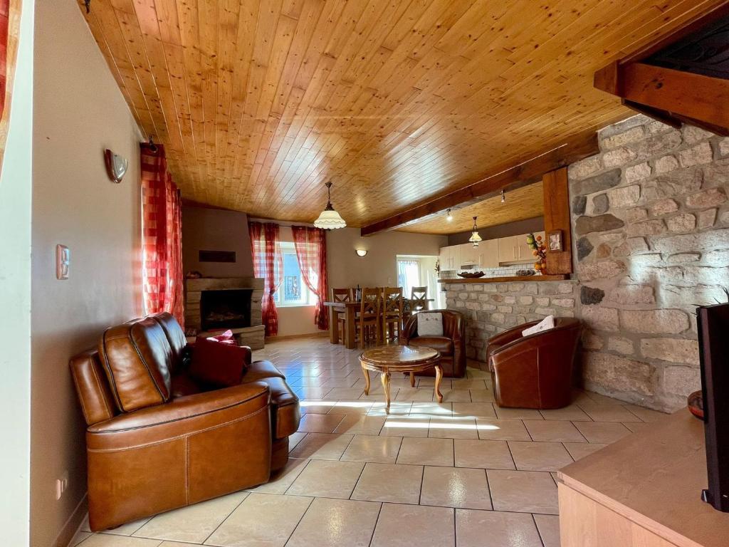 a living room with leather furniture and a stone wall at Gîte chaleureux avec cheminée près du Puy-en-Velay, idéal pour familles et séjours professionnels - FR-1-582-349 in Saint-Germain-Laprade