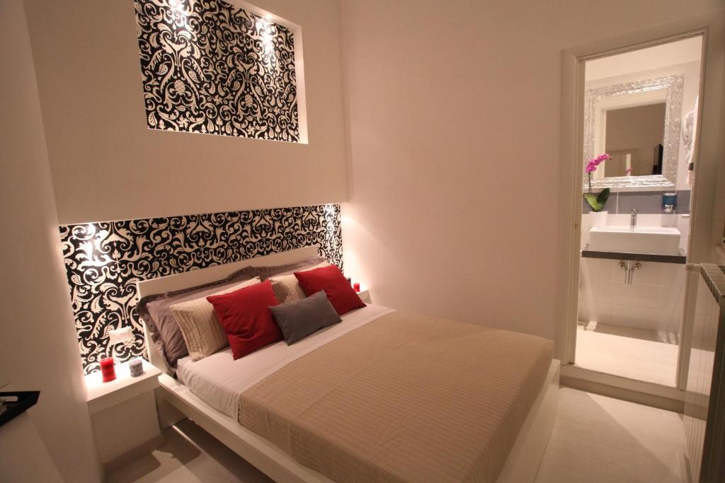 ローマにあるInterno 7 Luxury Rooms B&Bのベッドルーム1室(赤い枕と鏡付きのベッド1台付)