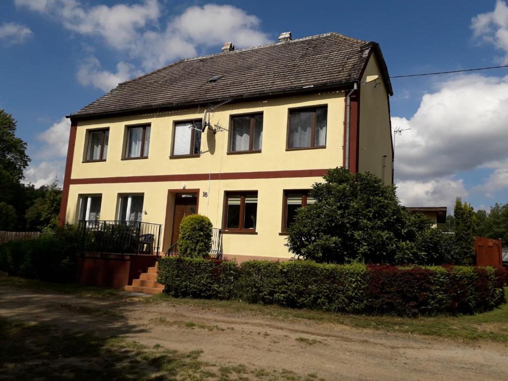 a large yellow house with a black roof at Wiktorówka in Torzym