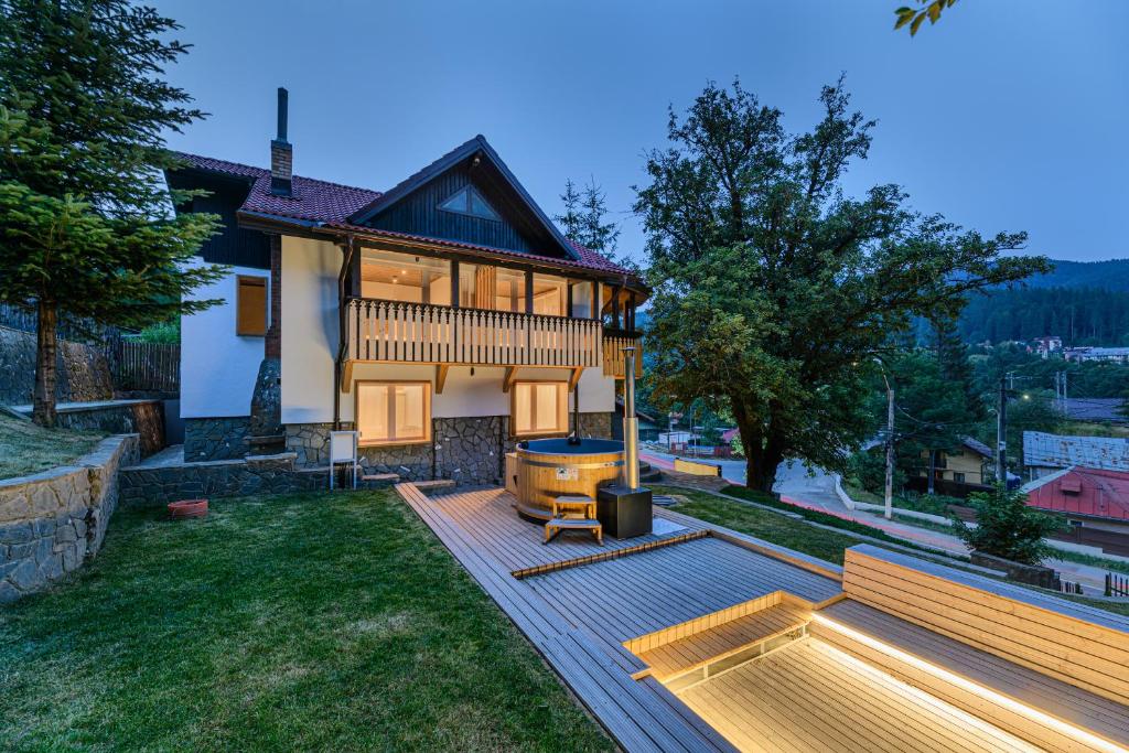 a house with a backyard with a wooden deck at Blend Mountain Villa in Buşteni