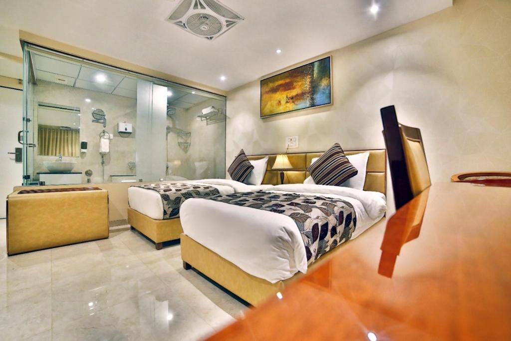 a large bedroom with two beds and a bathroom at Hotel Kings Heritage Surat in Surat
