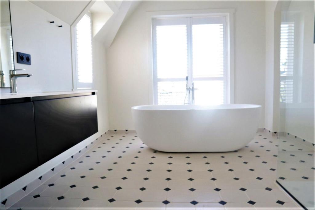 a bathroom with a tub on a tiled floor at Villa Zomerrust in De Panne