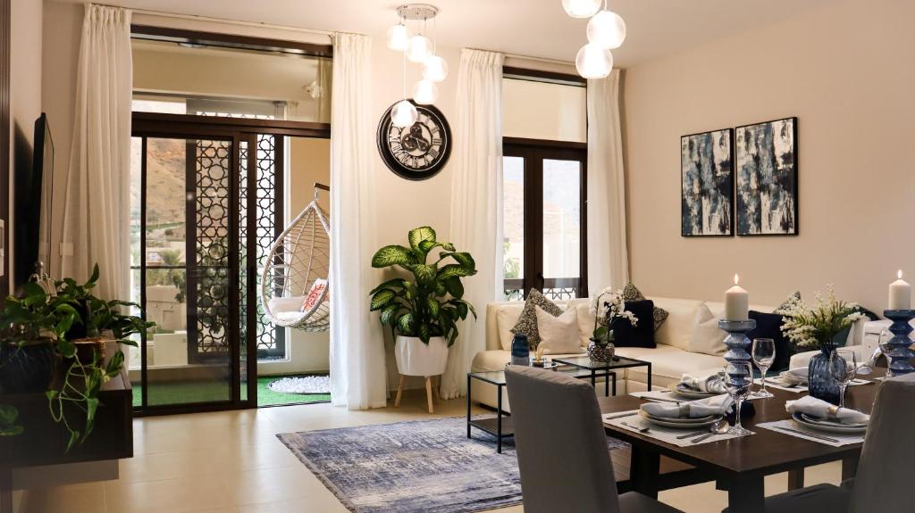 a dining room and living room with a table and chairs at Stylish Apartment with a Jacuzzi (Park&Pool View) in Muscat