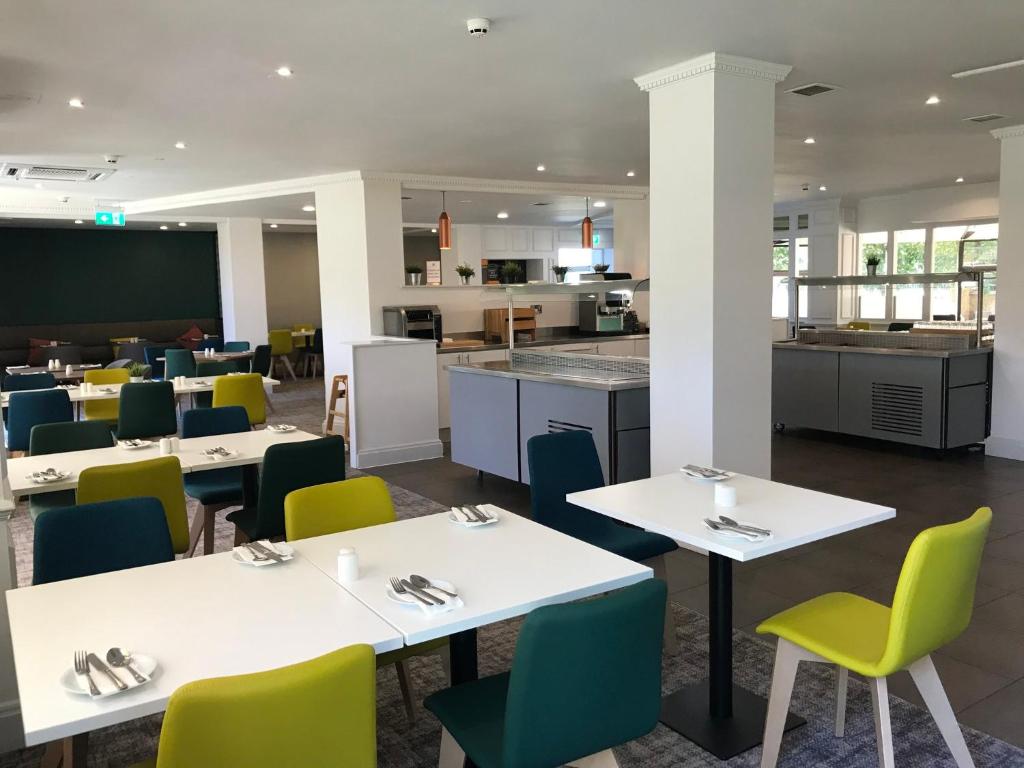 uma cafetaria com mesas e cadeiras e uma cozinha em Holiday Inn Doncaster A1- M Jct 36, an IHG Hotel em Doncaster