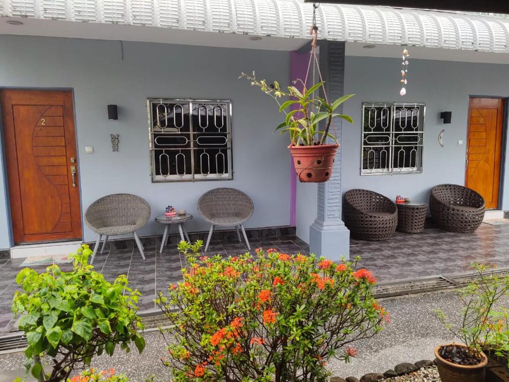 een patio met rieten stoelen en een potplant bij OCEAN LODGE in Pantai Cenang
