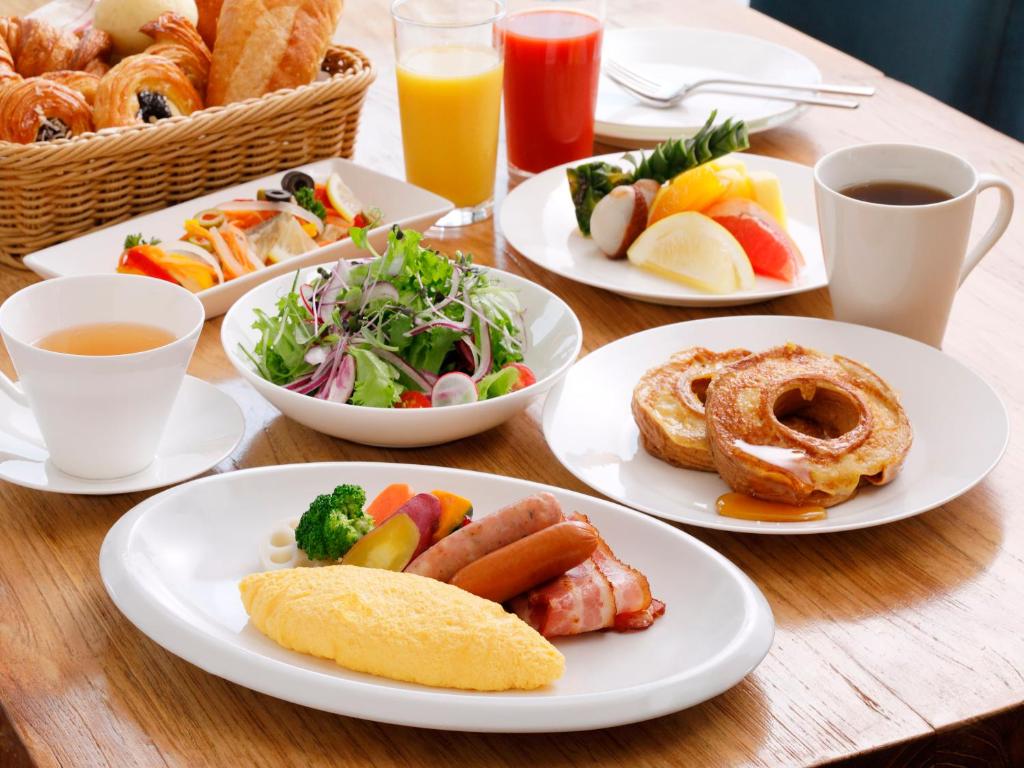 a wooden table with plates of food and drinks at Hotel Nikko Kanazawa in Kanazawa