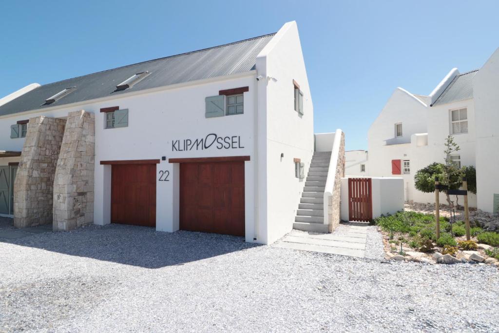 a white house with a garage and a driveway at Klipmossel - Bek Bay in Paternoster