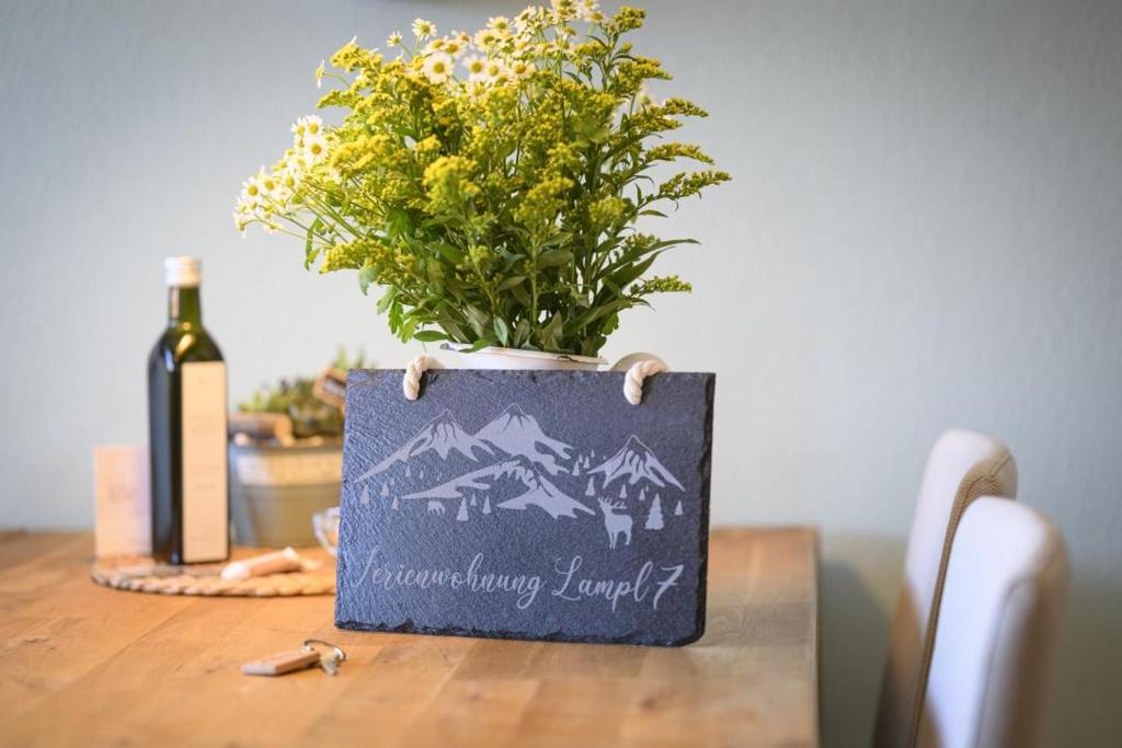 eine Flasche Wein und eine Vase mit Blumen auf dem Tisch in der Unterkunft Ferienwohnung Lampl 7 in Bad Kohlgrub