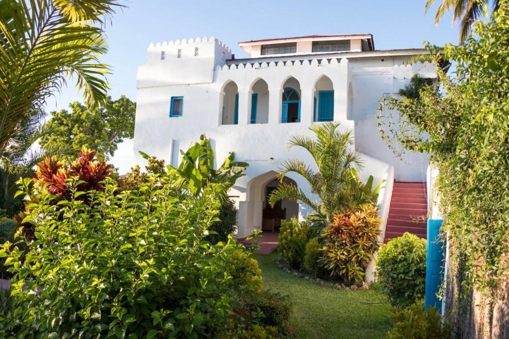 una casa blanca rodeada de árboles y plantas en The House of Royals en Zanzíbar