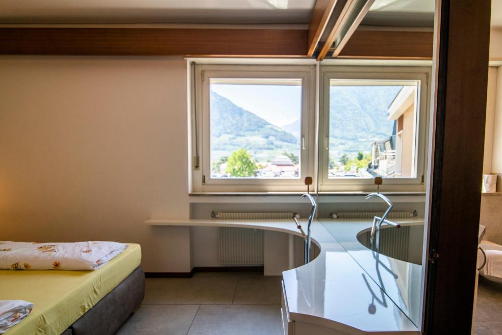 a room with a glass table and two windows at Theatre Lodge Attico teatro in Merano