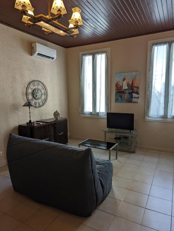 uma sala de estar com um sofá e uma televisão em le cocooning marseillais bis em Marselha