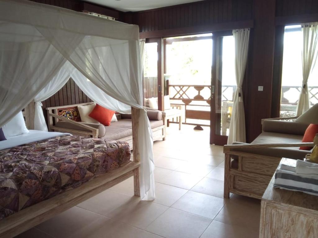 ein Schlafzimmer mit einem Bett, einem Sofa und Fenstern in der Unterkunft BINTANG MUNDUK in Munduk