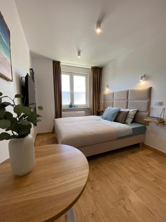 Un dormitorio con una cama y una mesa. en La Playa Apartments en Hel