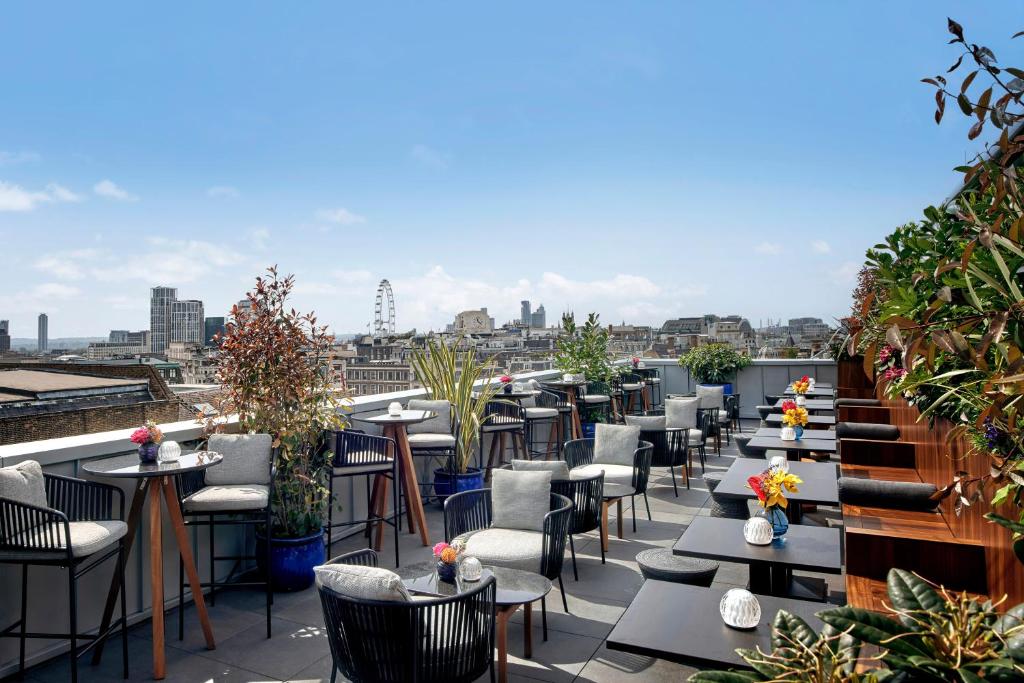 AMANO Covent Garden في لندن: صف من الطاولات والكراسي على فناء على السطح