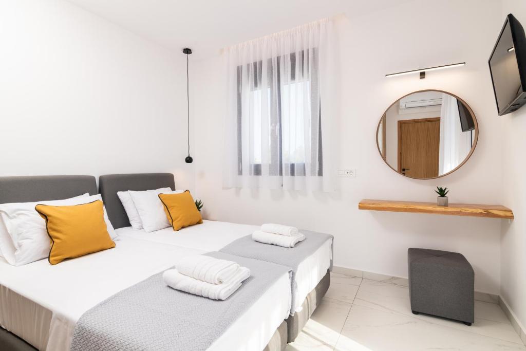 two beds in a white room with a mirror at Eagle's Nest - Adjoining Villas! in Tsilivi