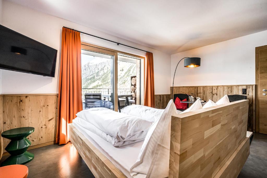 sypialnia z dużym łóżkiem i dużym oknem w obiekcie Mondschein Hotel & Chalet w mieście Stuben am Arlberg