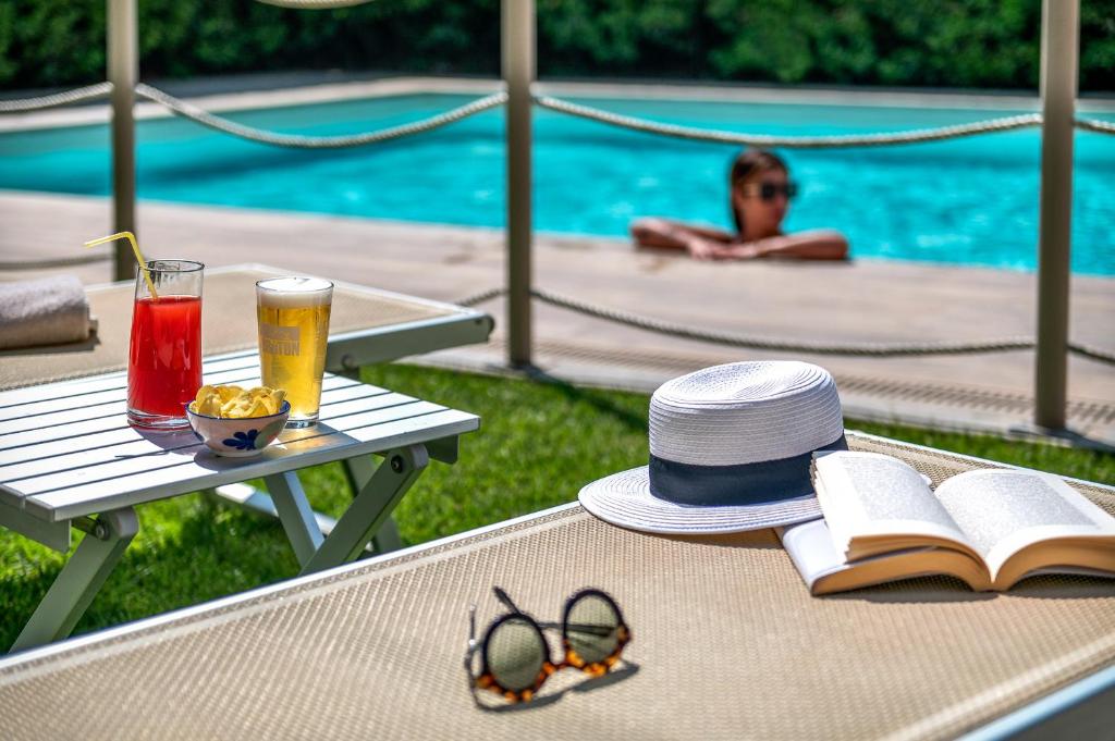 a table with a hat and a book next to a pool at Hotel San Marco in Lucca