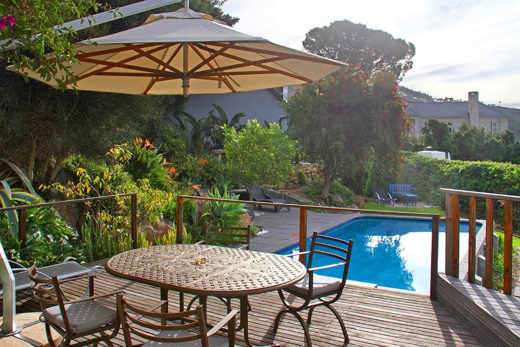 a table and chairs with an umbrella next to a pool at Cape Paradise Lodge and Apartments in Cape Town
