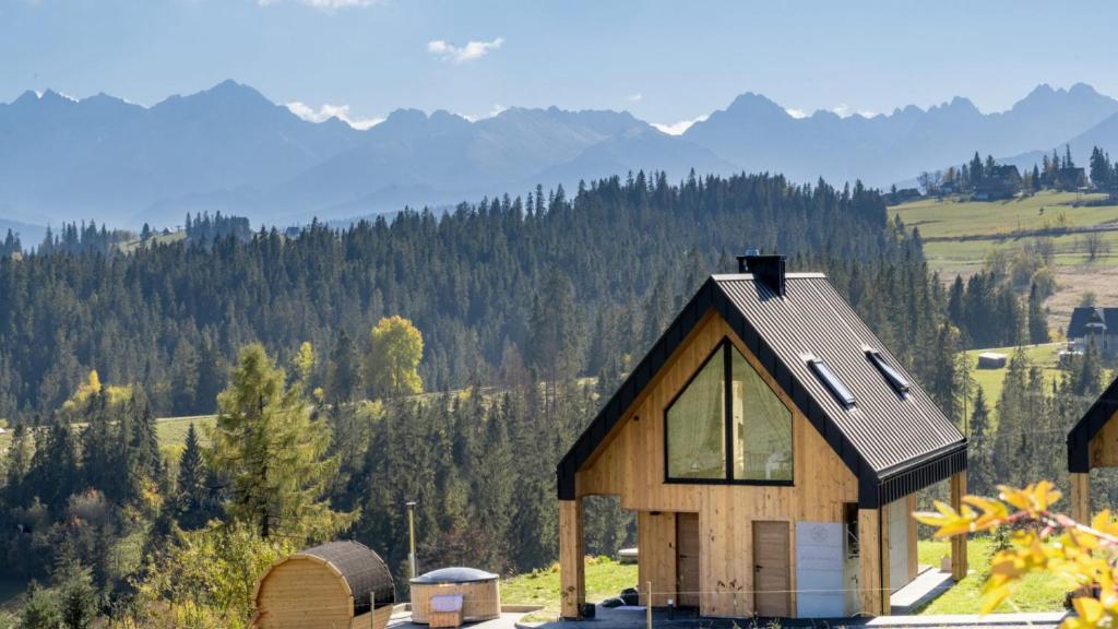 a house on a hill with mountains in the background at Sielsko Anielsko Tatry Jacuzzi & Sauna in Białka Tatrzanska