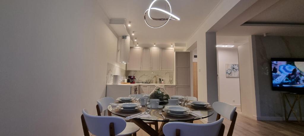 a dining room table with white chairs and a television at Zamkowa Park Luxury Apartment in Węgorzewo