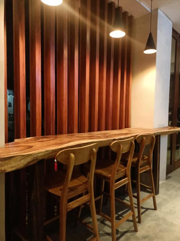 a wooden bar with four chairs in front of a wall at The Kd Suites & Coffee Shop in Munggu
