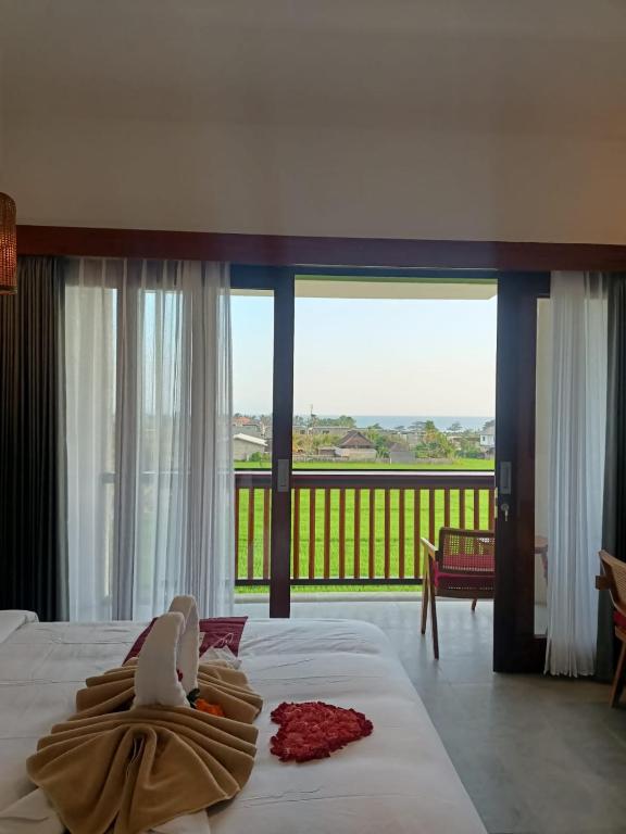 a hotel room with a bed and a balcony at The Kd Suites & Coffee Shop in Munggu