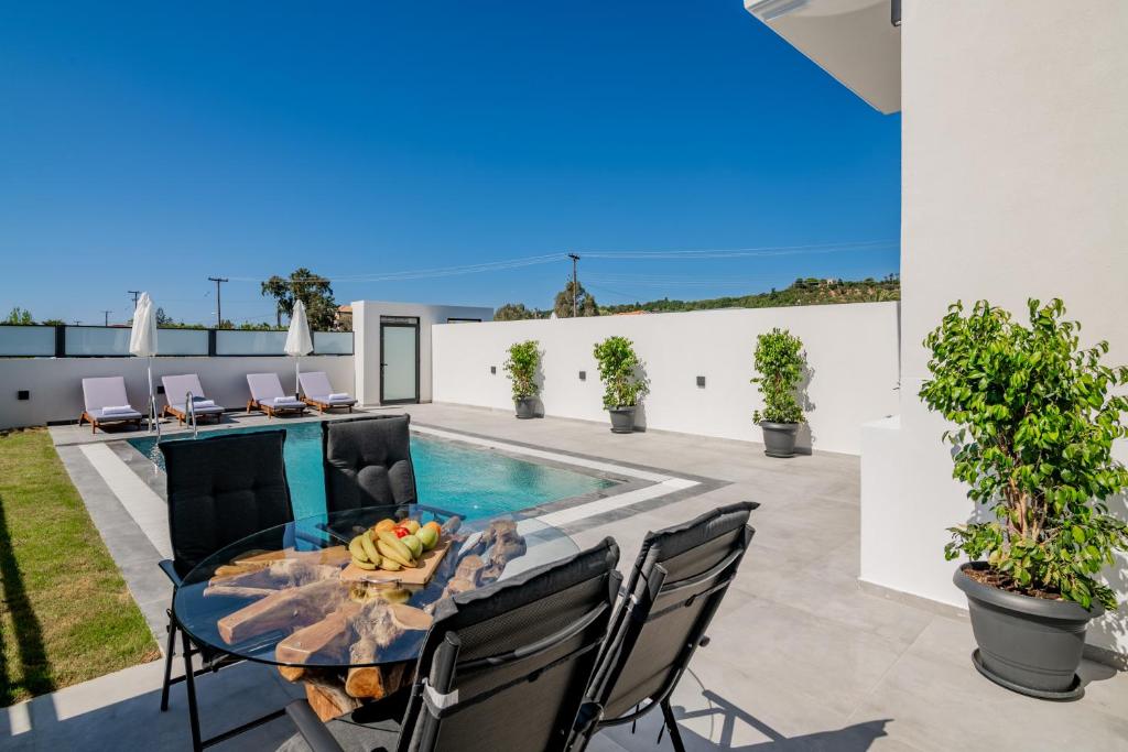 a patio with a table and chairs and a swimming pool at Eagle's Nest - Adjoining Villas! in Tsilivi