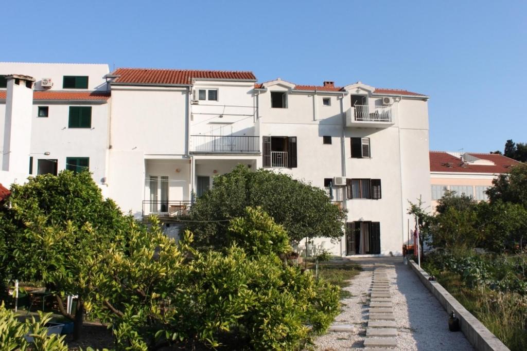 un edificio blanco con árboles delante de él en Apartments by the sea Drvenik Donja vala, Makarska - 6675, en Drvenik