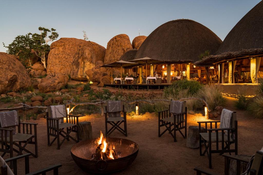 eine Feuerstelle vor einem Restaurant mit Stühlen und Tischen in der Unterkunft Mowani Mountain Camp in Khorixas