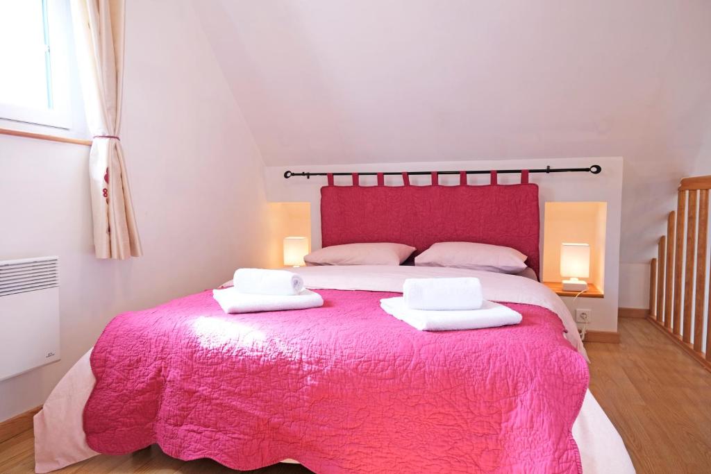 a bedroom with a pink bed with two towels on it at Lescoat-le petit paradis in Plestin-les-Grèves