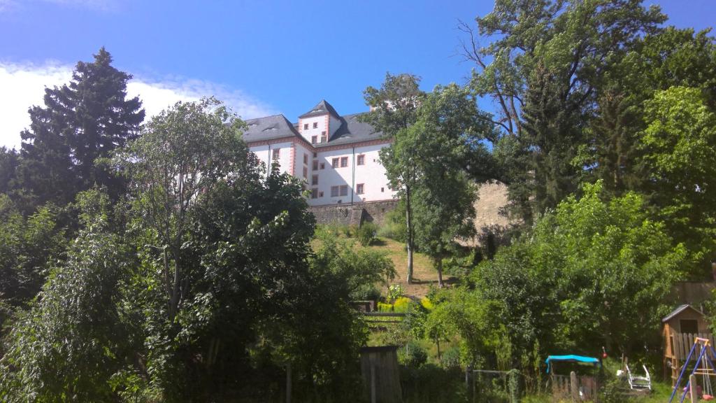 Ferienwohnung Augustusburg في أوغسطبورغ: منزل أبيض على قمة تل به أشجار